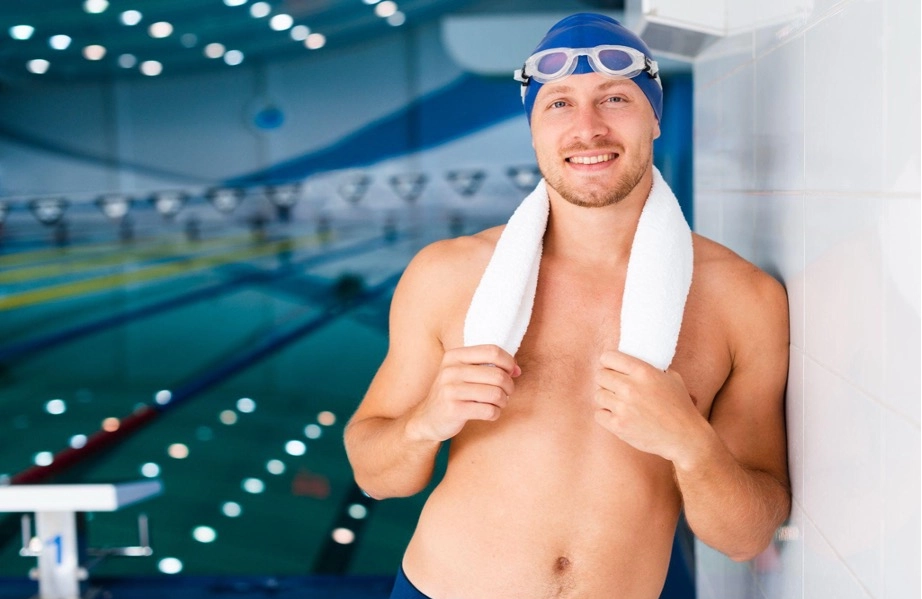 Male swimmer with a towel at an indoor pool