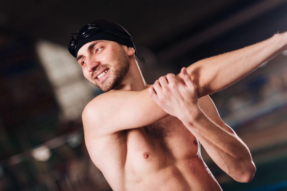 Male swimmer stretching before training.