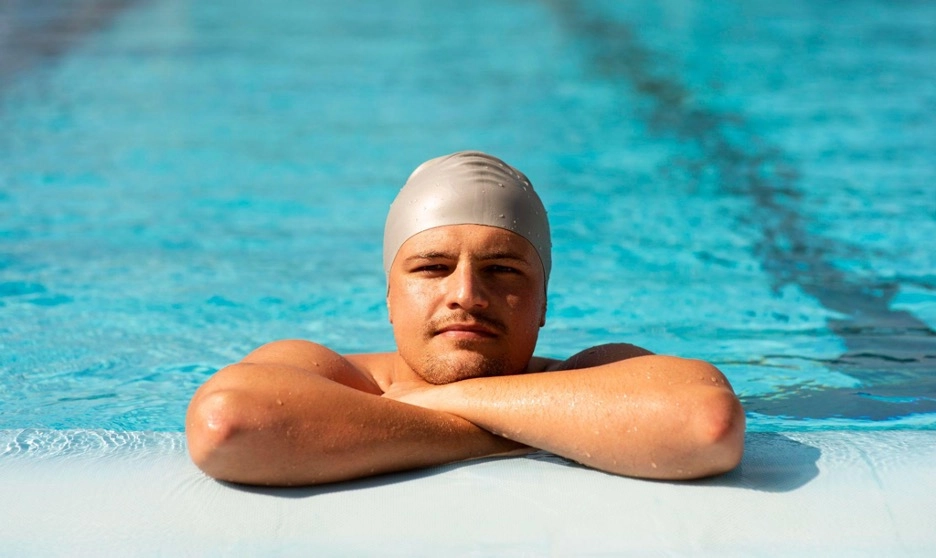 Male swimmer resting at the pool edge.