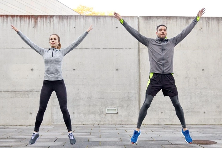 A man and a woman doing jumping jacks