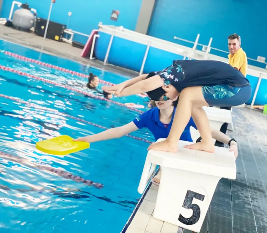 Child preparing to dive while an instructor offers guidance on the side