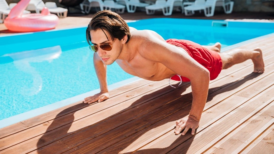 Man doing push-ups beside a pool