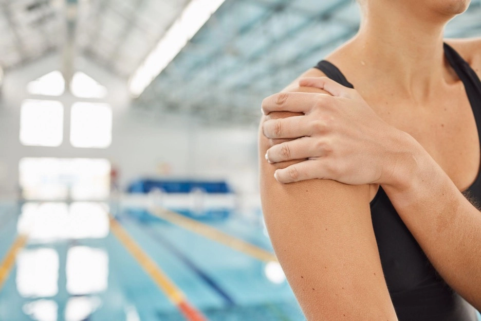 Female swimmer holding her shoulder after a swimming session